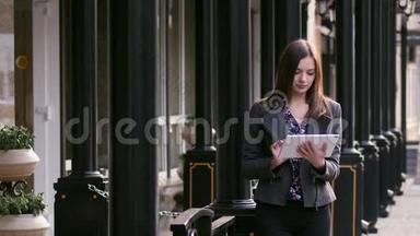 美丽的年轻女商人，在<strong>商务酒店</strong>附近的夕阳下，在街上使用平板电脑